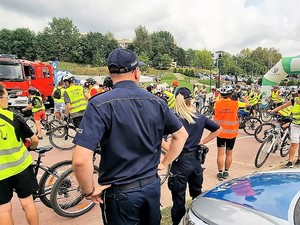 policjanci stoją przed uczestnikami rajdu rowerowego