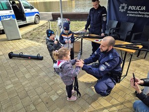 policjant uśmiecha się do stojących przed nim dzieci podczas wydarzenia sportowego