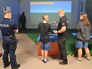 policjant prowadzi zajęcia na strzelnicy multimedialnej podczas dnia otwartego szkoły